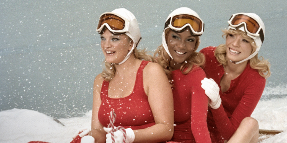 three women in red outfits and ski goggles on sled