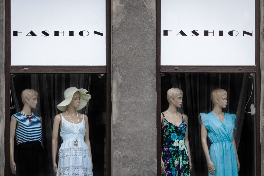 four mannequins in a store window with the word "fashion" written on the glass
